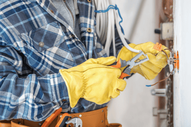 electrician with yellow electrical gloves on working on electrical components